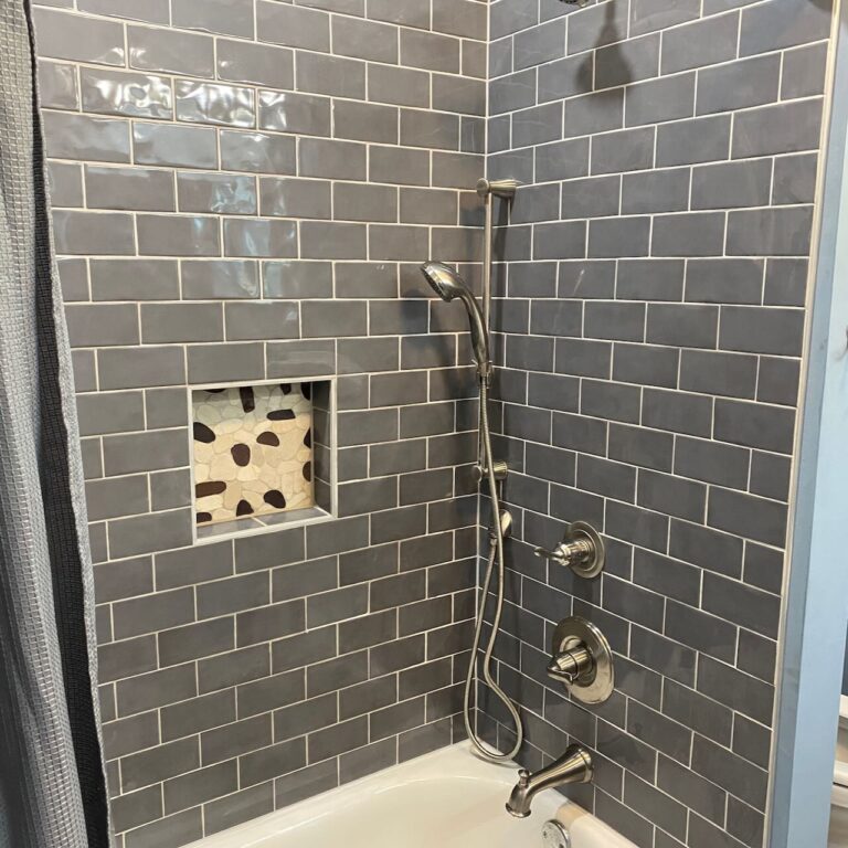 Tile installer. Pictured is a tub shower combo with blue subway tiles. We install tile showers, tile flooring and tile backsplashes.